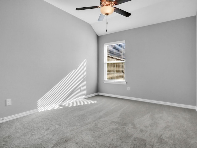 carpeted empty room with a ceiling fan, vaulted ceiling, and baseboards