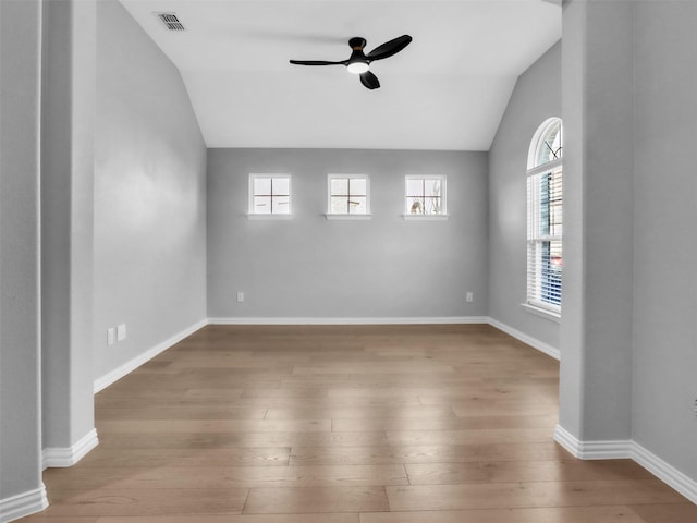 empty room featuring ceiling fan, visible vents, vaulted ceiling, and wood finished floors