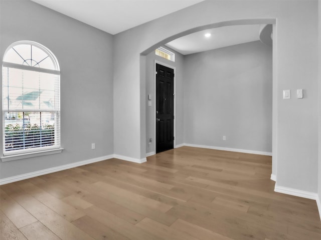 entrance foyer with light wood finished floors, baseboards, and arched walkways