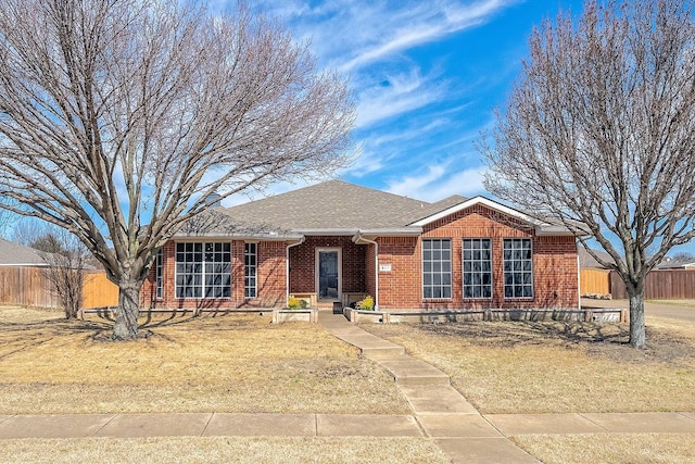 ranch-style house with a shingled roof, fence, and brick siding