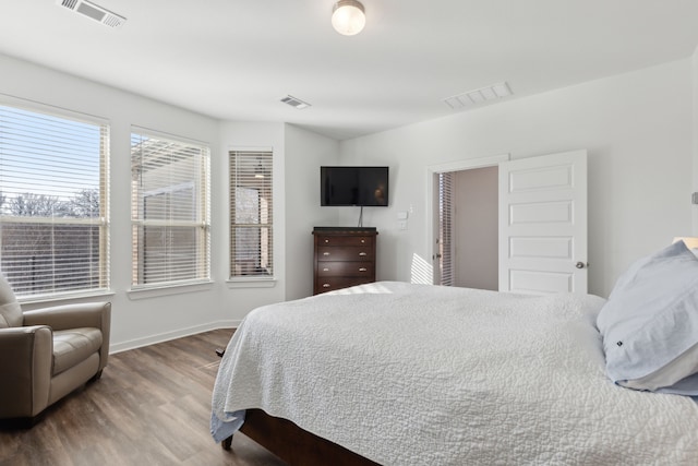 bedroom featuring wood finished floors, visible vents, and baseboards