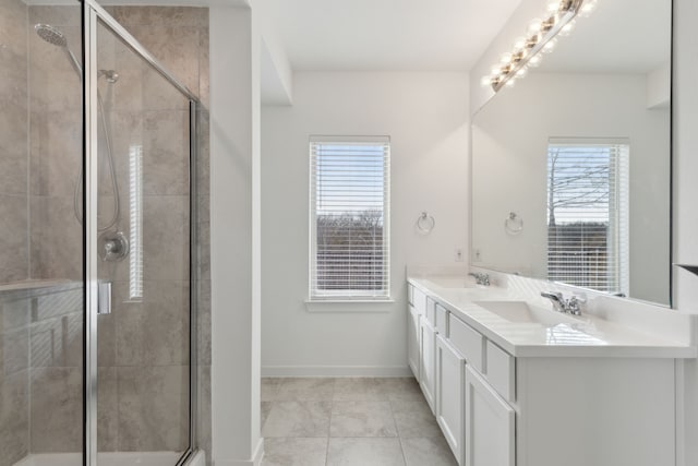 full bathroom with double vanity, a stall shower, a sink, and baseboards