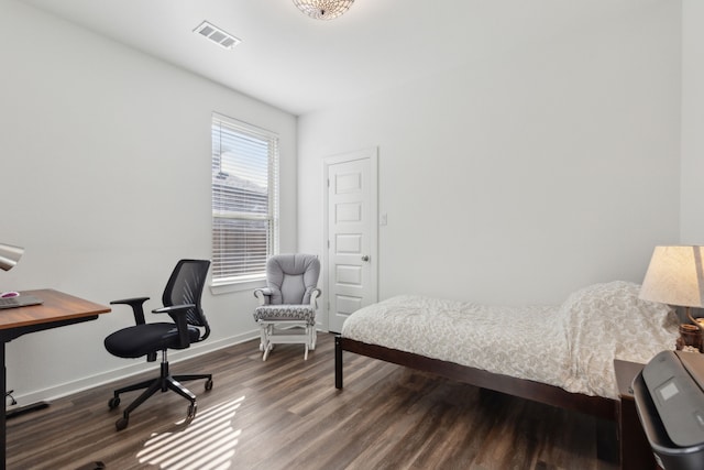 bedroom with baseboards, visible vents, and wood finished floors