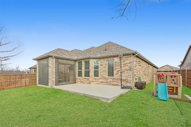 back of property with a playground, a yard, brick siding, a patio area, and a fenced backyard