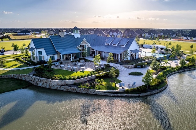 rear view of house with metal roof, a patio, a water view, and a residential view