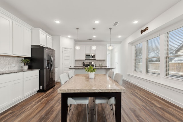 kitchen with dark wood-type flooring, a breakfast bar, white cabinetry, appliances with stainless steel finishes, and a center island with sink