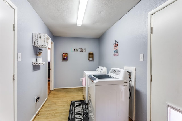 laundry room with laundry area, baseboards, a textured ceiling, light wood-type flooring, and washing machine and dryer