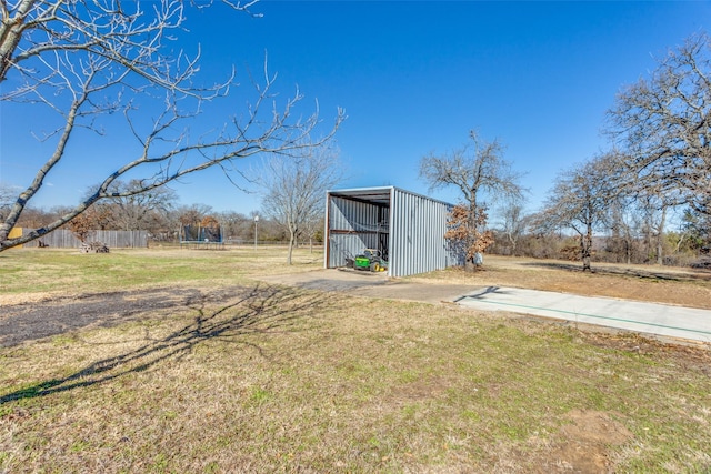 view of yard featuring an outbuilding, an outdoor structure, fence, concrete driveway, and a carport