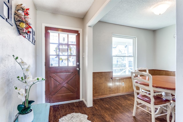 foyer featuring wainscoting, wood walls, a textured ceiling, and wood finished floors