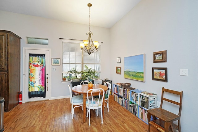 dining space featuring a chandelier, light wood finished floors, and baseboards