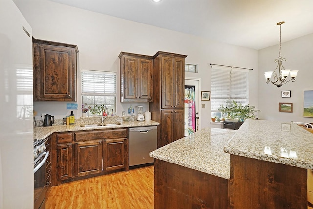 kitchen with appliances with stainless steel finishes, dark brown cabinetry, a sink, and light wood finished floors