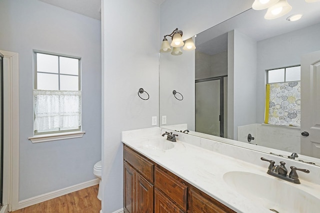 full bathroom with double vanity, a stall shower, a sink, and toilet