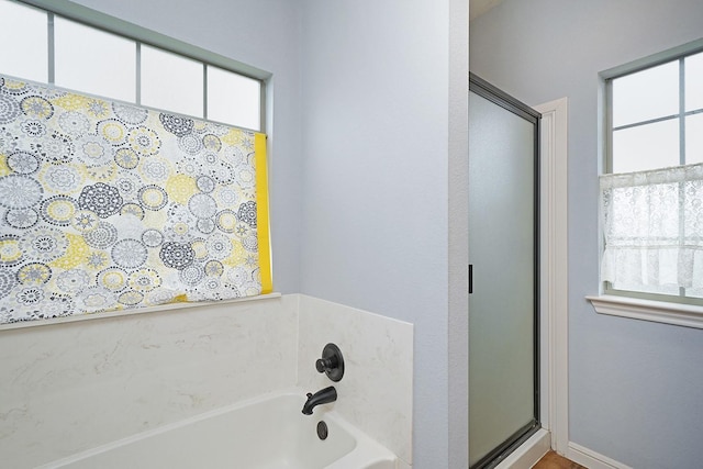 full bathroom with a stall shower, plenty of natural light, and a bath