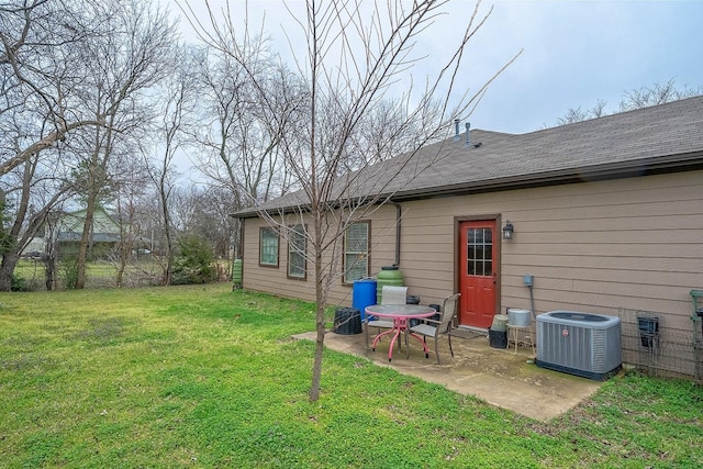 rear view of property featuring a shingled roof, cooling unit, a patio area, and a yard