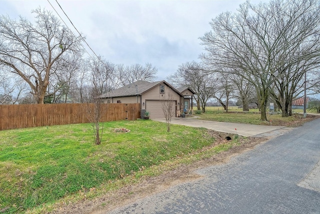 exterior space with an attached garage, fence, concrete driveway, and a yard