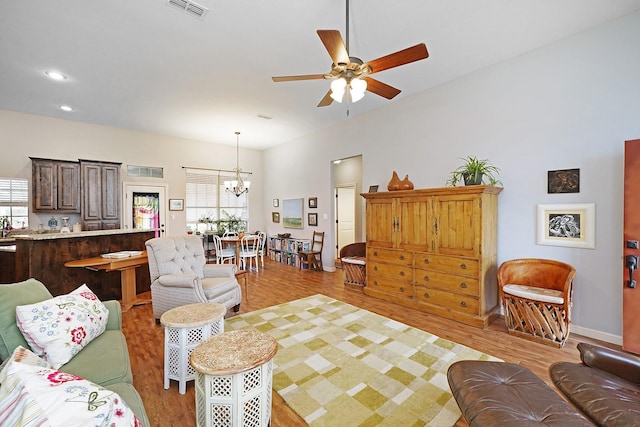 living room with recessed lighting, visible vents, light wood-type flooring, baseboards, and ceiling fan with notable chandelier