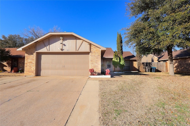 view of front of home featuring concrete driveway, brick siding, an attached garage, and fence