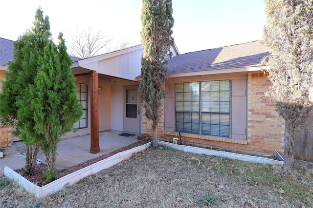 back of house featuring roof with shingles and brick siding