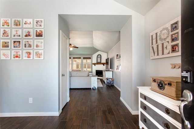 hall featuring baseboards, vaulted ceiling, and dark wood-type flooring