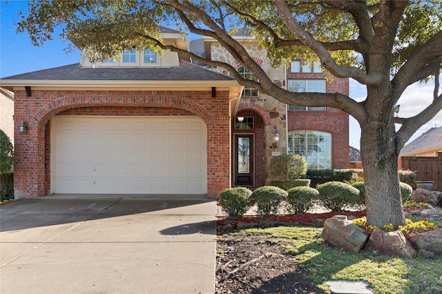 view of front of house featuring a garage, concrete driveway, brick siding, and roof with shingles