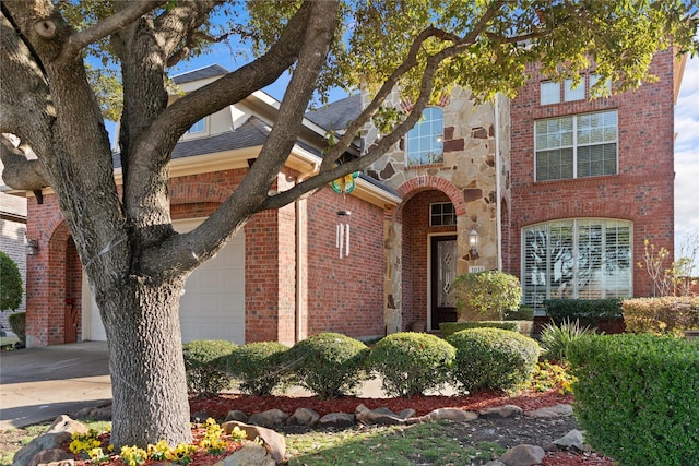 view of front facade featuring stone siding, brick siding, driveway, and an attached garage