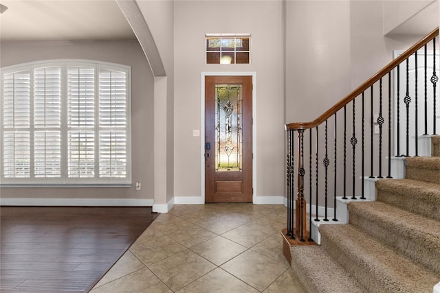 entrance foyer featuring stairs, plenty of natural light, baseboards, and tile patterned floors