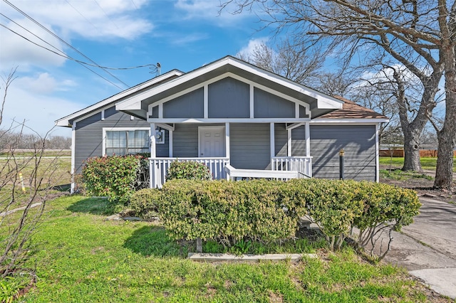 bungalow-style home featuring covered porch, board and batten siding, and a front lawn