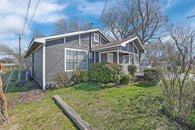 view of side of property featuring a yard, central air condition unit, and a porch