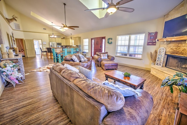 living room featuring a stone fireplace, a wealth of natural light, and wood finished floors