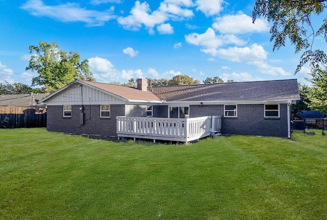 back of house with a deck, brick siding, fence, a yard, and a chimney