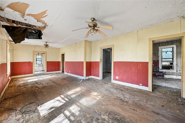 unfurnished room featuring attic access, wainscoting, ceiling fan, a textured ceiling, and hardwood / wood-style floors