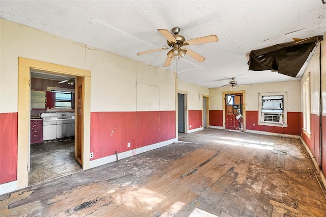 unfurnished room featuring ceiling fan, a textured ceiling, cooling unit, a sink, and wainscoting