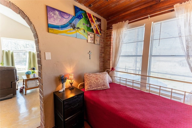 bedroom featuring arched walkways, wood ceiling, and finished concrete floors