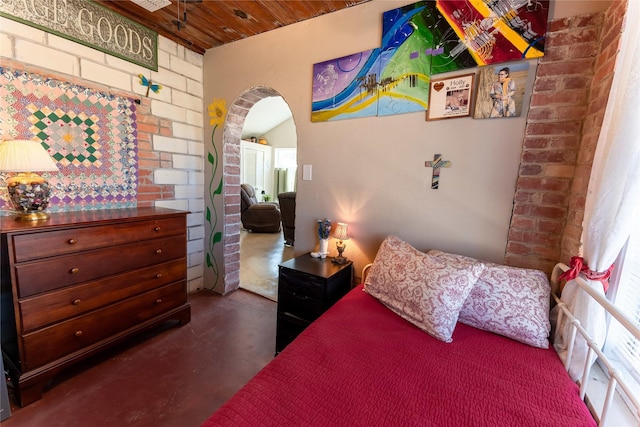 bedroom featuring finished concrete flooring, brick wall, and wood ceiling
