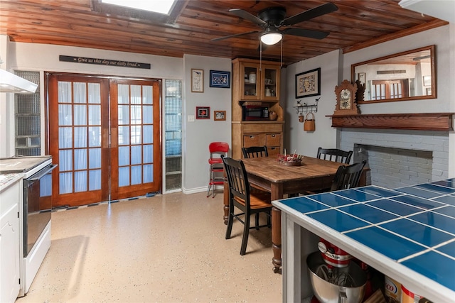 dining space with french doors, a fireplace, wooden ceiling, and a ceiling fan