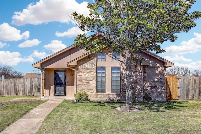 view of front of home featuring brick siding, a gate, fence, and a front yard