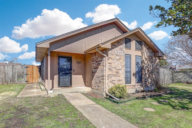 view of front of property featuring a gate, fence, a front lawn, and brick siding