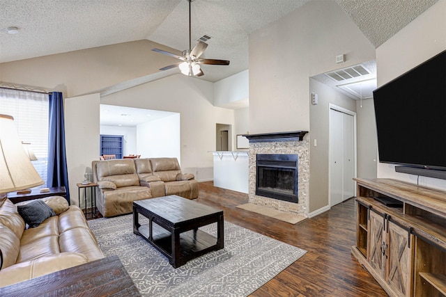 living room featuring ceiling fan, visible vents, wood finished floors, and a stone fireplace