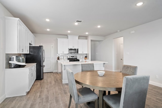 dining area featuring light wood-style flooring, visible vents, baseboards, and recessed lighting