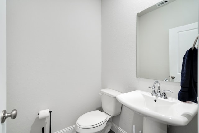 bathroom with toilet, baseboards, visible vents, and a sink