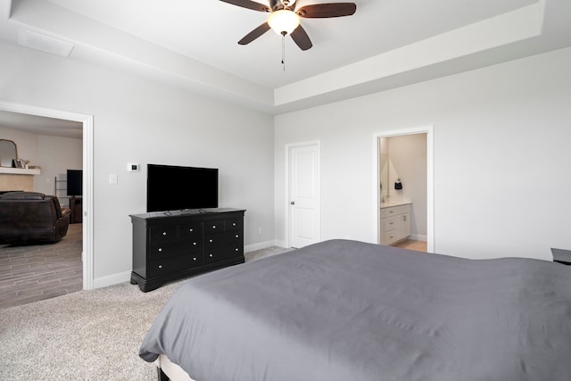 bedroom featuring baseboards, a raised ceiling, a ceiling fan, connected bathroom, and light colored carpet