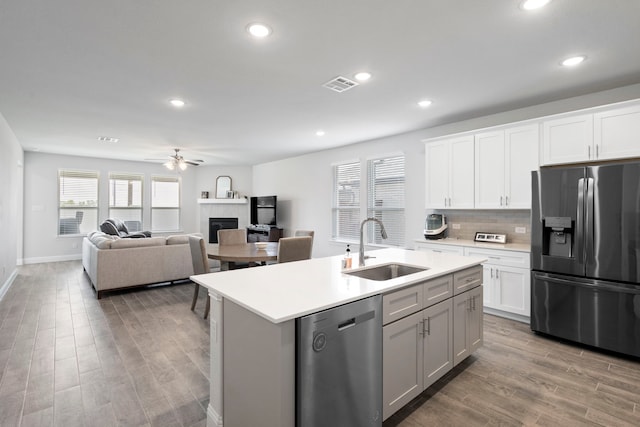 kitchen with stainless steel appliances, visible vents, a tiled fireplace, a sink, and light wood-type flooring