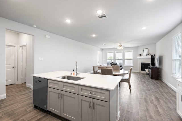 kitchen with a fireplace, visible vents, gray cabinetry, stainless steel dishwasher, and a sink