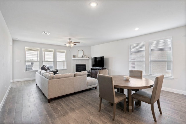 dining room with a glass covered fireplace, wood finished floors, visible vents, and baseboards