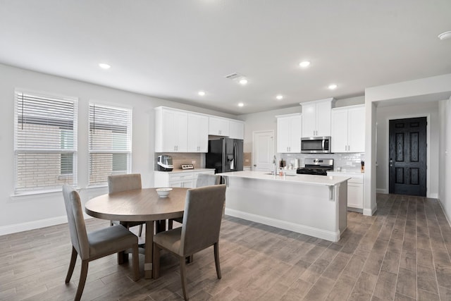 kitchen featuring stainless steel appliances, backsplash, a kitchen island with sink, and visible vents