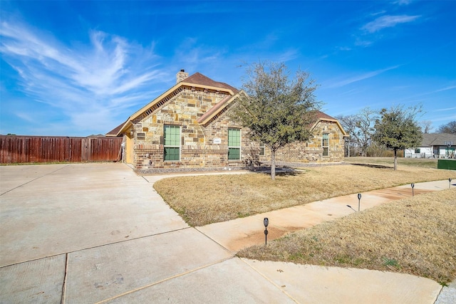 view of front of house featuring brick siding, fence, stone siding, a front lawn, and a chimney