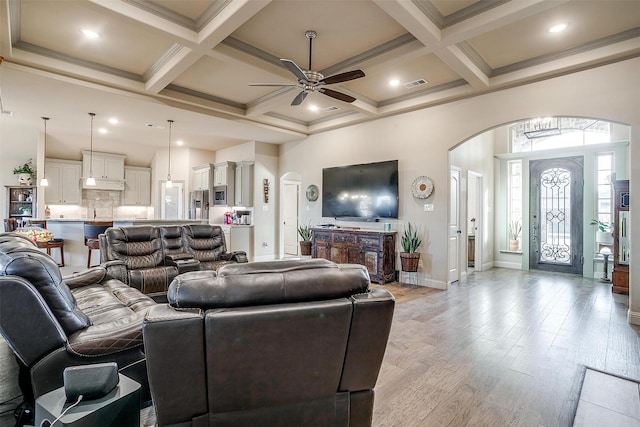 living area with visible vents, arched walkways, a towering ceiling, light wood-style floors, and beam ceiling