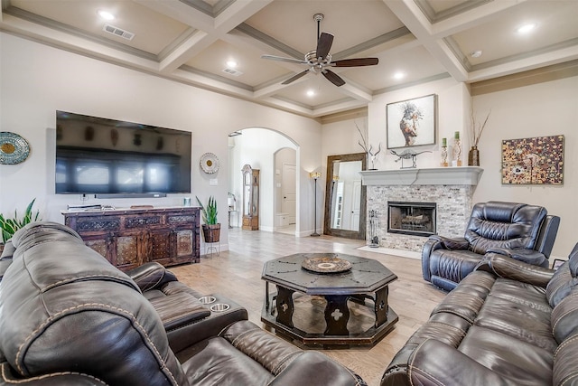 living room featuring arched walkways, beamed ceiling, a fireplace, and visible vents