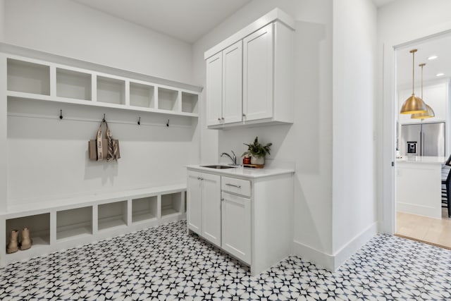 mudroom featuring light floors, baseboards, a sink, and recessed lighting