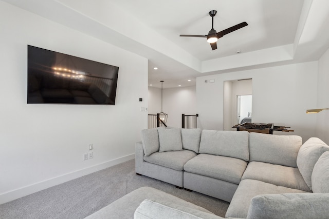 carpeted living area with a tray ceiling, recessed lighting, a ceiling fan, and baseboards